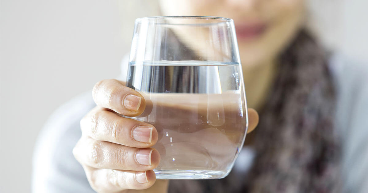 Woman holding out a glass of water